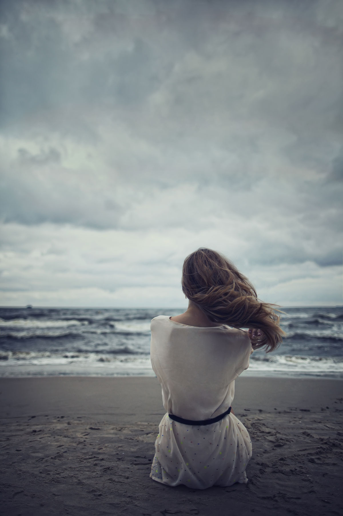 A depressed woman on a cold beach